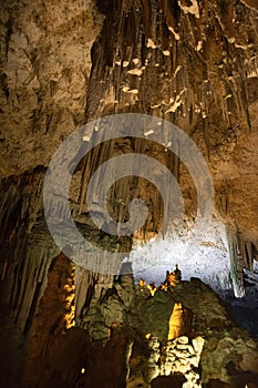 Horizontal view of the ceiling and floor of a cave with a close-up of stalagtites and stalagmites