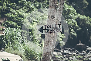 A horizontal view of classic simple design handmade wooden sign of toilet give direction to WC. Bali.