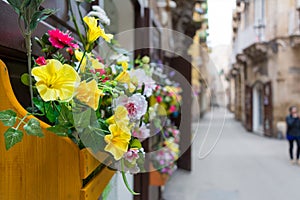 Horizontal View of Close Up of a Composition of Flowers in a Yellow Wooden Box Hanged on a Door in a Street. Taranto, South of It