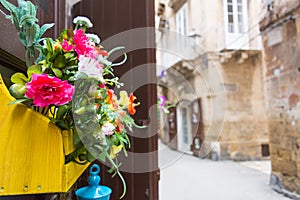 Horizontal View of Close Up of a Composition of Flowers in a Yellow Wooden Box Hanged on a Door in a Street. Taranto, South of It