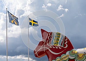 Horizontal view of a colorful Swedish Dala horse and the Swedish flag under an expressive sky photo