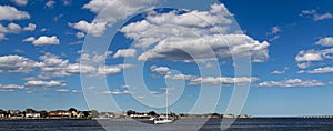 Horizontal view of puffy clouds over sailboat in Great South Bay