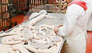 Horizontal view. A worker prepares sausages on a table at a meat processing factory, food industry