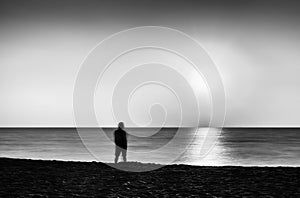Horizontal vivid black and white lonely man meeting ocean sunset
