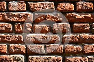 Horizontal wall texture of several rows of very old brickwork made of red brick. Shattered and damaged brick wall with pinched co