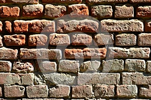 Horizontal wall texture of several rows of very old brickwork made of red brick. Shattered and damaged brick wall with pinched co