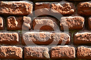 Horizontal wall texture of several rows of very old brickwork made of red brick. Shattered and damaged brick wall with pinched co