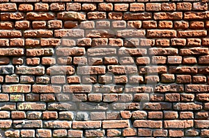 Horizontal wall texture of several rows of very old brickwork made of red brick. Shattered and damaged brick wall with pinched co