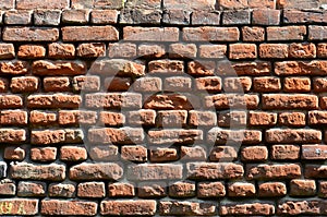 Horizontal wall texture of several rows of very old brickwork made of red brick. Shattered and damaged brick wall with pinched co