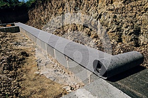 Long line of rolled bitumen waterproofing material in two layers lies on the masonry of concrete blocks photo