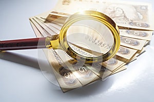 Horizontal white background shot from the top of many 5 yuan notes and magnifying glass photo