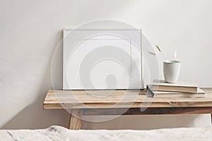 Horizontal white frame mockup on vintage wooden bench, table. Ceramic mug with dry Lagurus ovatus grass and books. White photo