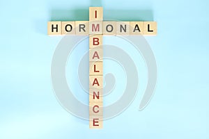 Hormonal imbalance concept. Wooden blocks crossword puzzle flat lay in blue background.