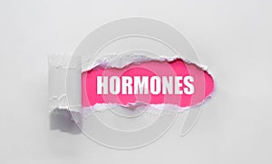 HORMONES medical word written under torn paper