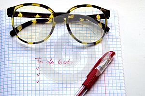 Horn-rimmed glasses, red ink pen on a checkered notebook photo