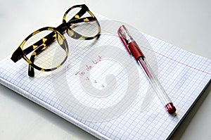 Horn-rimmed glasses, red ink pen on a checkered notebook photo