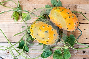 Horned melon, vine with two fresh ripe kiwano, Cucumis metuliferus, on wooden background