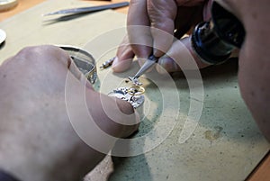 Horology artisan with tongs fixing a wristwatch photo