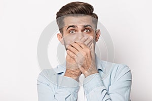 Horrified man covering mouth with hands looking at camera photo