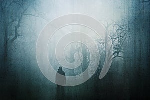 A horror concept of a figure in a spooky forest on a moody, foggy winters day. With a grunge, abstract edit
