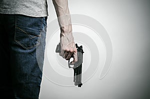 Horror and firearms topic: crazed killer with a gun on a gray background in the studio photo