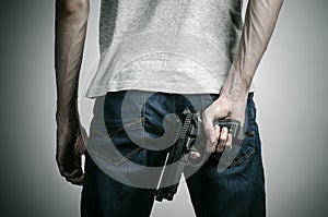 Horror and firearms topic: crazed killer with a gun on a gray background in the studio