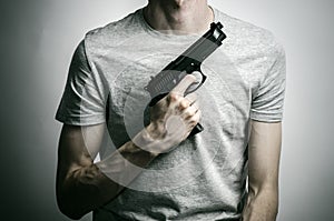 Horror and firearms topic: suicide with a gun on a gray background in the studio