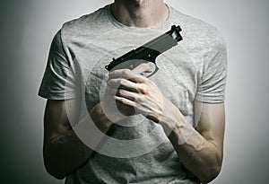 Horror and firearms topic: suicide with a gun on a gray background in the studio