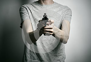 Horror and firearms topic: suicide with a gun on a gray background in the studio