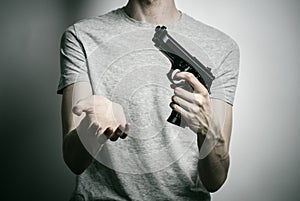 Horror and firearms topic: suicide with a gun on a gray background in the studio