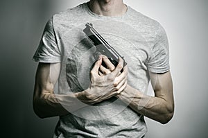 Horror and firearms topic: suicide with a gun on a gray background in the studio