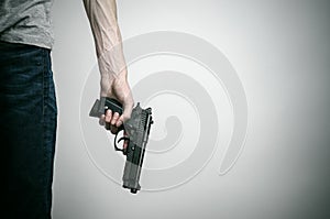 Horror and firearms topic: suicide with a gun on a gray background in the studio photo