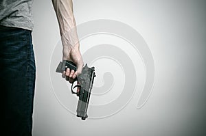 Horror and firearms topic: suicide with a gun on a gray background in the studio