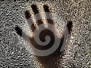 Horror hand. The shadow hand of human behind the glass. Corrugated textured glass through which children`s palm are visible