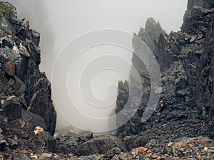 Horror mountain shadows. Dramatic fog among giant rocky mountains. Ghostly atmospheric view to big cliff. Low clouds and beautiful