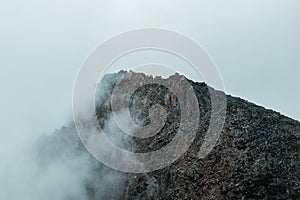 Horror mountain shadows. Dramatic fog among giant rocky mountains. Ghostly atmospheric view to big cliff. Low clouds and beautiful