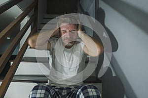 Horror movie style portrait of sad and desperate man in pajamas suffering depression problem or mental disorder sitting on