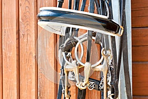 Horse bridle hanging on stable wooden door. Closeup outdoors.