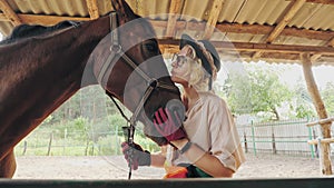 horse care. equestrian sport hobby. beautiful rider girl, horsewoman is stroking and hugging her horse at horse farm or