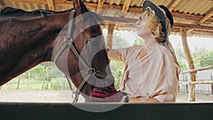 horse care. equestrian sport hobby. beautiful rider girl, horsewoman is stroking and hugging her horse at horse farm or