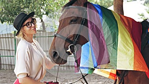 horse care. equestrian sport hobby. rainbow flag. a rider girl, stroking and hugging her horse