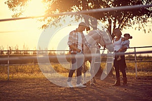 Horse enjoying the family presence. Young happy family having fun at countryside outdoors. Sunset, golden hour