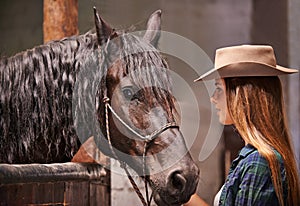 Horse, farm and ranch owner with woman in barn or stable for work in agriculture or sustainability. Cowgirl, texas or