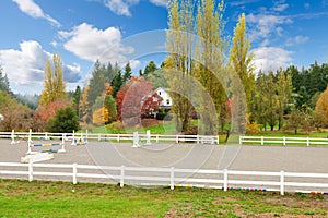 Horse farm with white fence and fall colorful leaves.