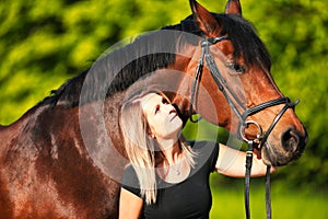 Horse and girl head portraits against a green background in the sunshine