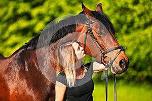 Horse and girl head portraits against a green background in the sunshine