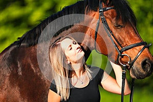 Horse and girl head portraits against a green background in the sunshine