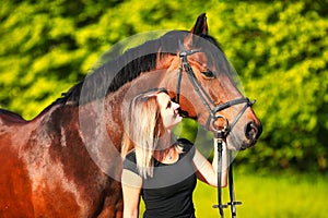 Horse and girl head portraits against a green background in the sunshine