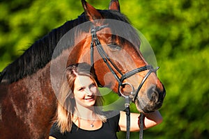 Horse and girl head portraits against a green background in the sunshine