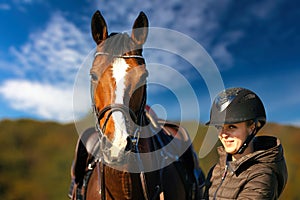 Horse head portraits in front of a blue sky and a rider standing next to it.